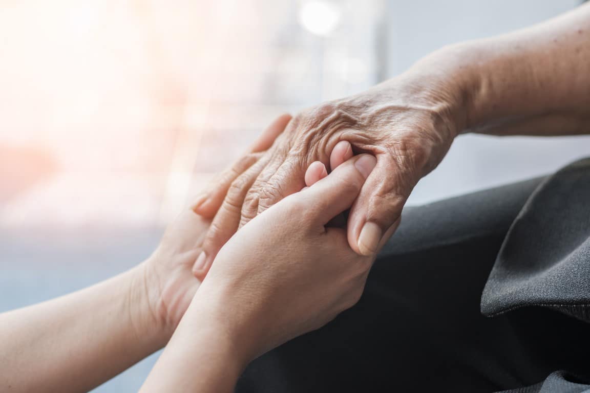 personne qui tient la main d'une personne atteinte d'Alzheimer